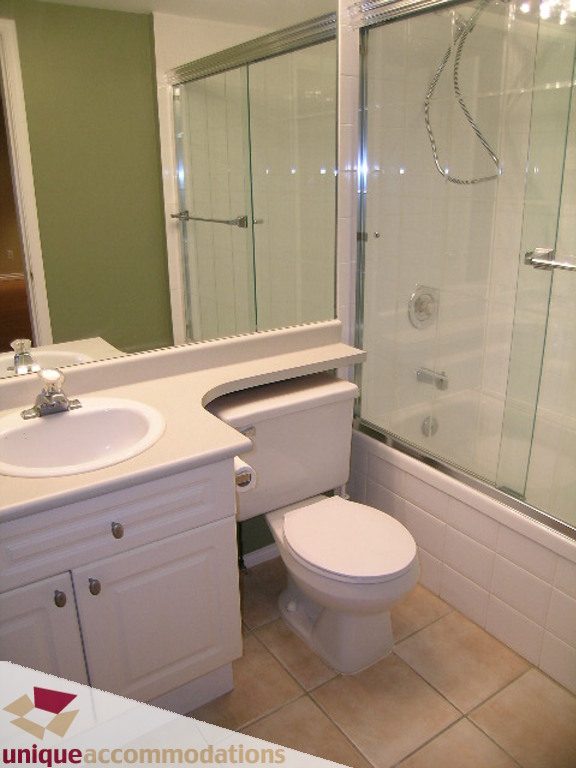 Bright bathroom with white vanity, toilet, and glass shower, clean and modern. - 208 - 128 West 8th Street, North Vancouver