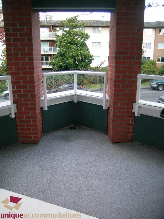 Balcony with brick pillars, green flooring, and city view. - 208 - 128 West 8th Street, North Vancouver