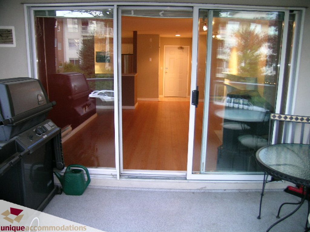 Furnished patio with sliding glass doors, hardwood floors, and outdoor grill. - 208 - 128 West 8th Street, North Vancouver