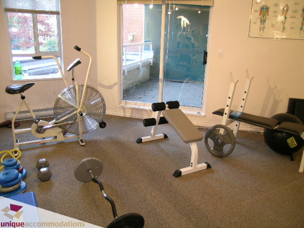 Fitness room with exercise equipment, weights, and a window view. - 208 - 128 West 8th Street, North Vancouver