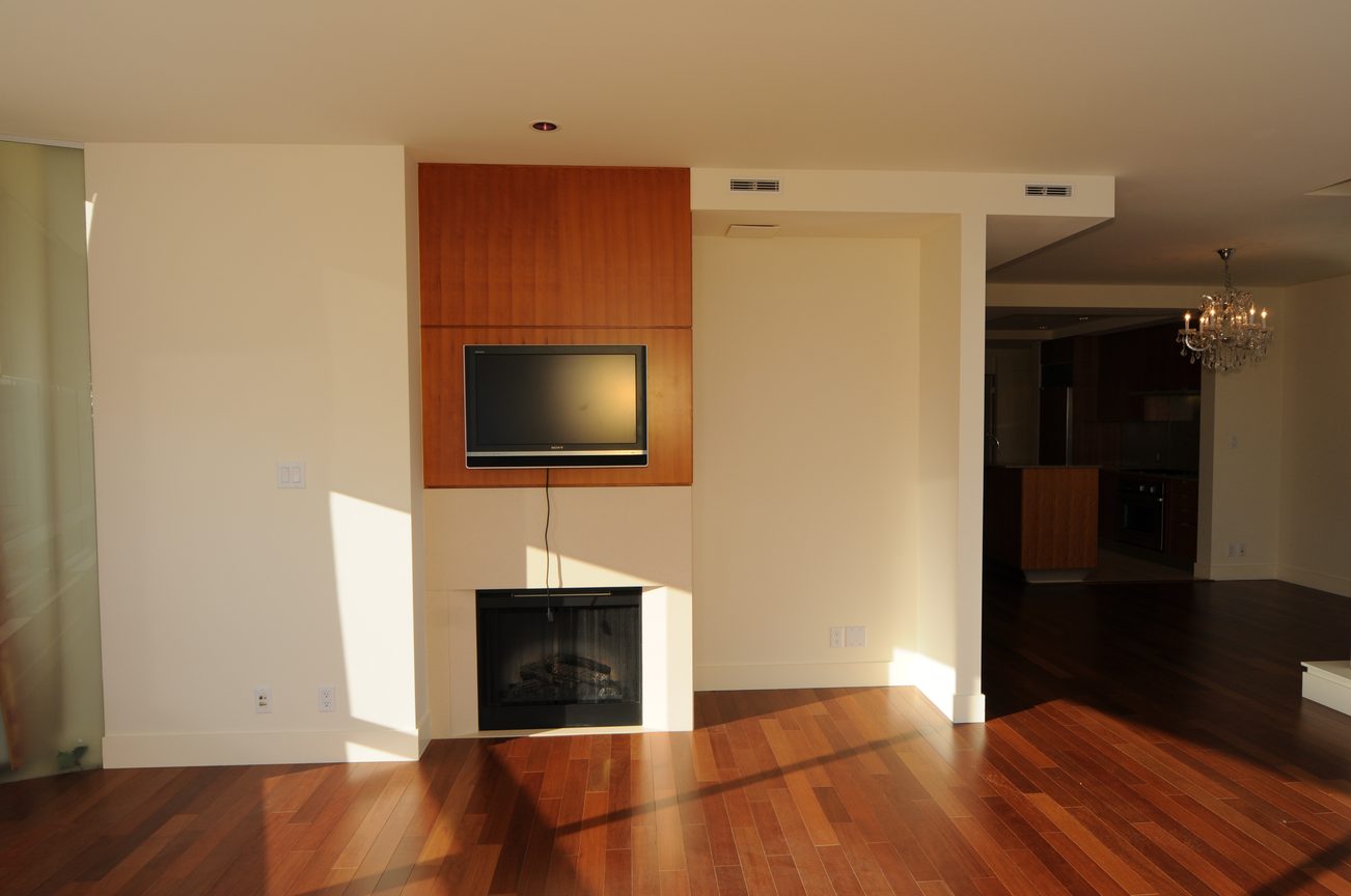Bright living room with hardwood floors, modern fireplace, and kitchen in the background. - 2304 - 1077 West Cordova St, Vancouver Downtown
