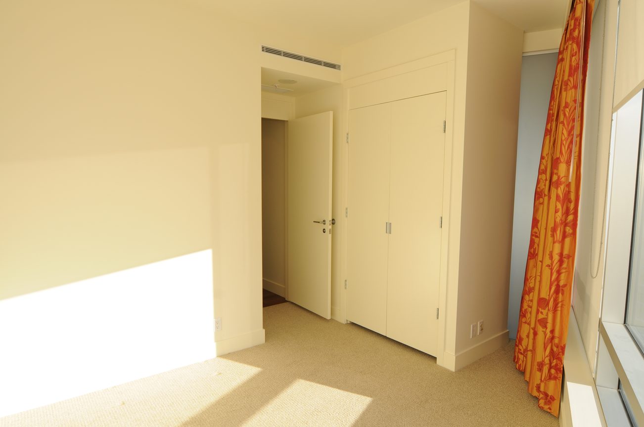 Bright bedroom with white walls, large closet, and orange floral curtains. - 2304 - 1077 West Cordova St, Vancouver Downtown