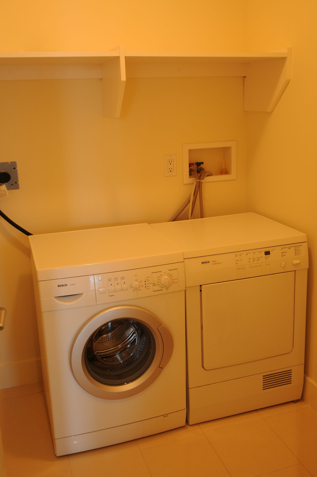 Laundry room with Bosch washer and dryer, white shelves above. - 2304 - 1077 West Cordova St, Vancouver Downtown