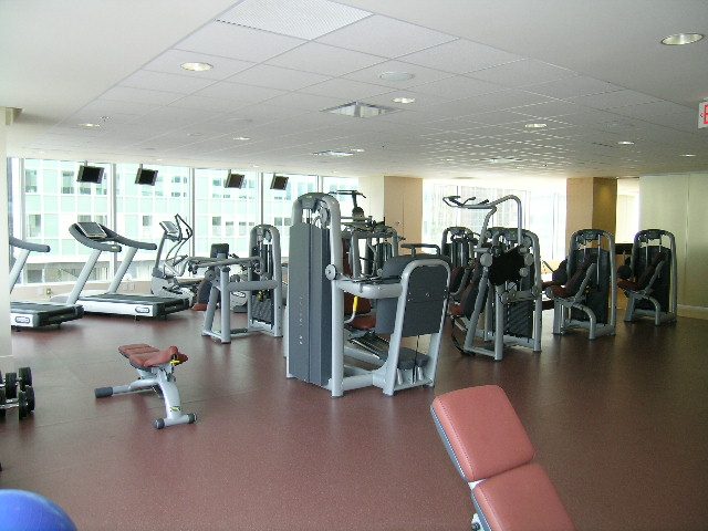 Fitness room with cardio machines and weight equipment, large windows offering city views. - 2304 - 1077 West Cordova St, Vancouver Downtown