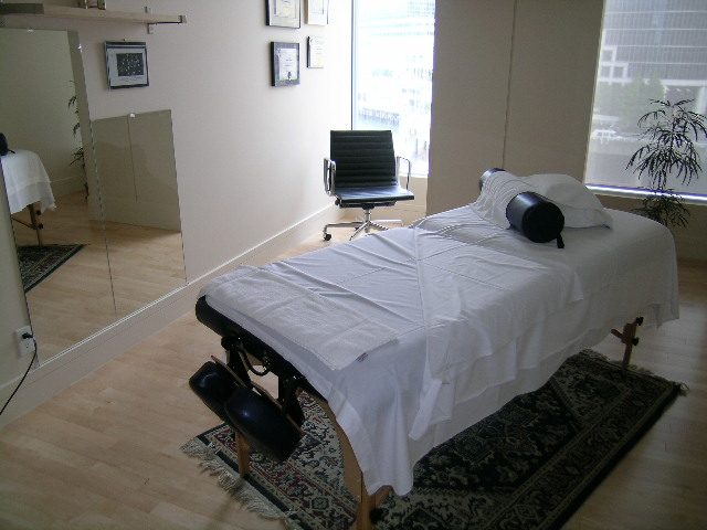 Bright living room with large windows, hardwood floors, and a cozy massage table setup. - 2304 - 1077 West Cordova St, Vancouver Downtown