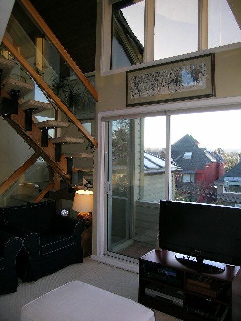 Living room with large windows, view of rooftops, and a modern staircase. - 1628 Stephens Street, Vancouver West Side