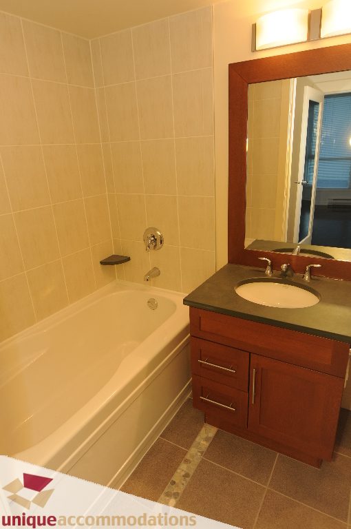 Bathroom with dark wood vanity, granite countertop, and bathtub. - 1802 - 1189 Melville Street, Vancouver Downtown