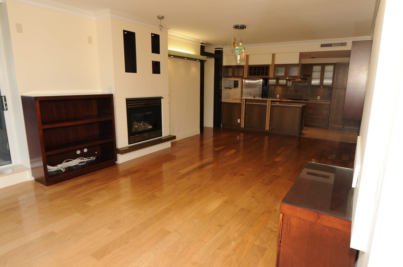 Bright living room with hardwood floors, modern fireplace, and kitchen in the background. - 2603 - 1483 Homer Street, Vancouver Downtown