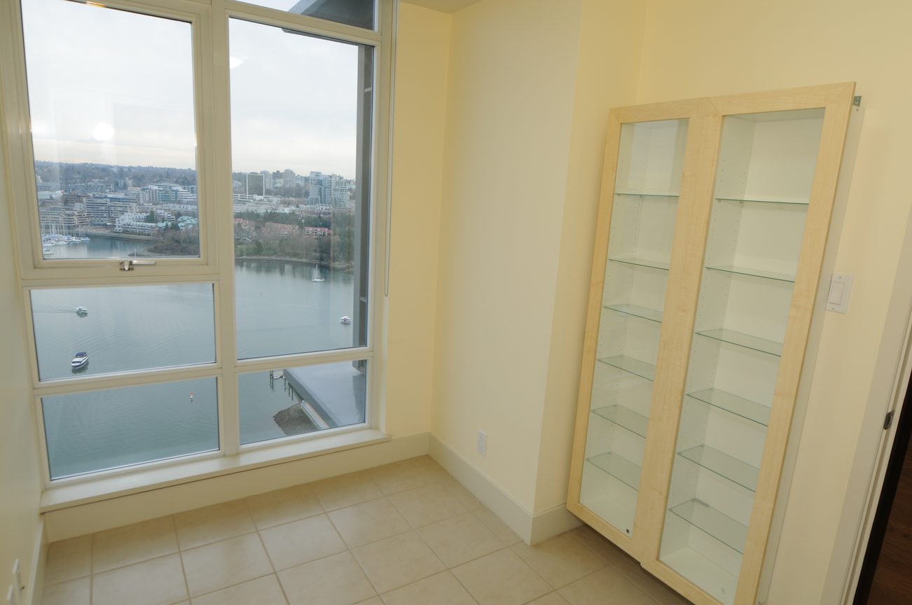Bright living room with large windows offering a city view, light wood shelving. - 2603 - 1483 Homer Street, Vancouver Downtown