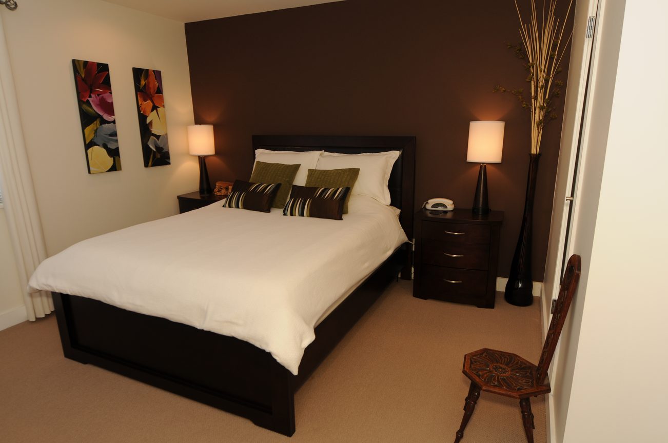 Spacious bedroom with dark brown walls, white bedding, and modern decor. - 4196 Norwood Avenue, North Vancouver