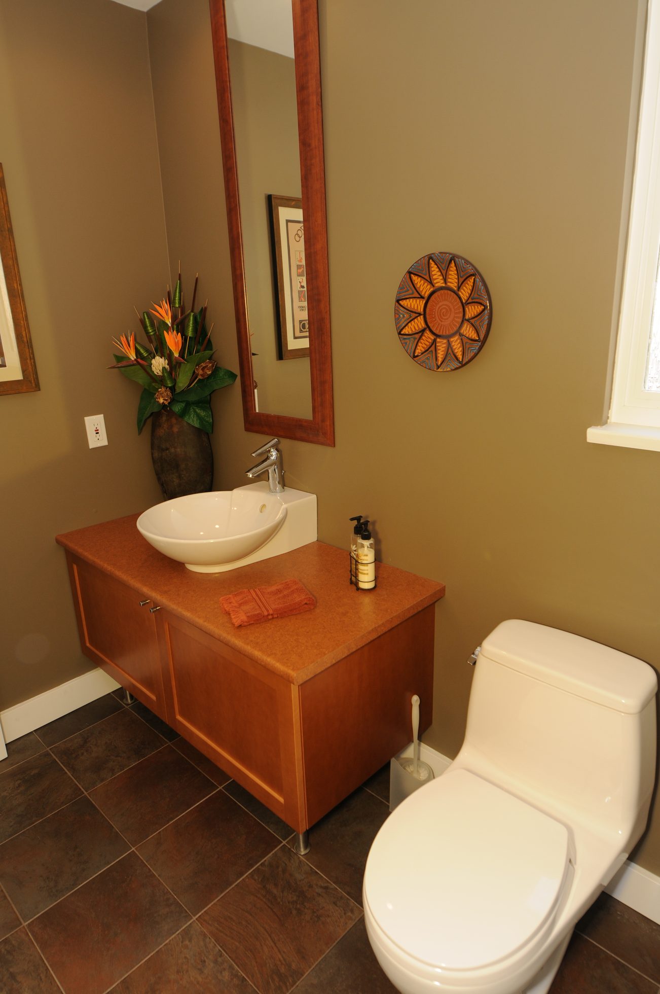 Bathroom with wooden vanity, modern sink, and decorative sun art. - 4196 Norwood Avenue, North Vancouver
