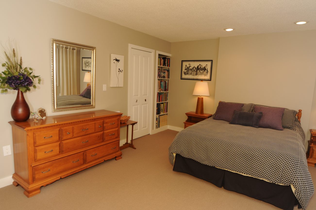 Spacious bedroom with wooden furniture, bookshelf, and framed art. - 4196 Norwood Avenue, North Vancouver