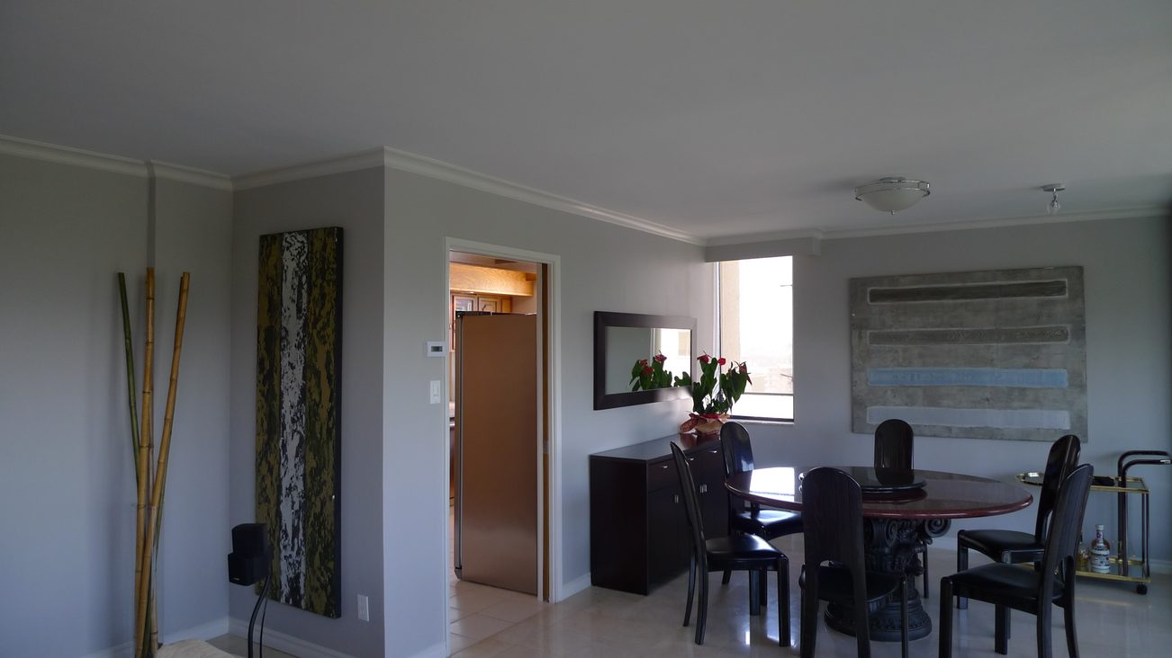 Furnished dining area with modern artwork, bamboo decor, and a view of the kitchen. - 1501 - 845 Chilco Street, Vancouver Downtown