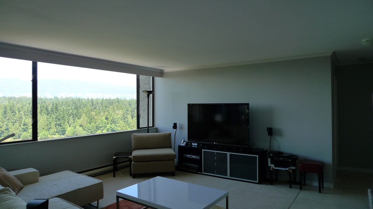 Living room with large window view, modern furniture, and flat-screen TV. - 1501 - 845 Chilco Street, Vancouver Downtown