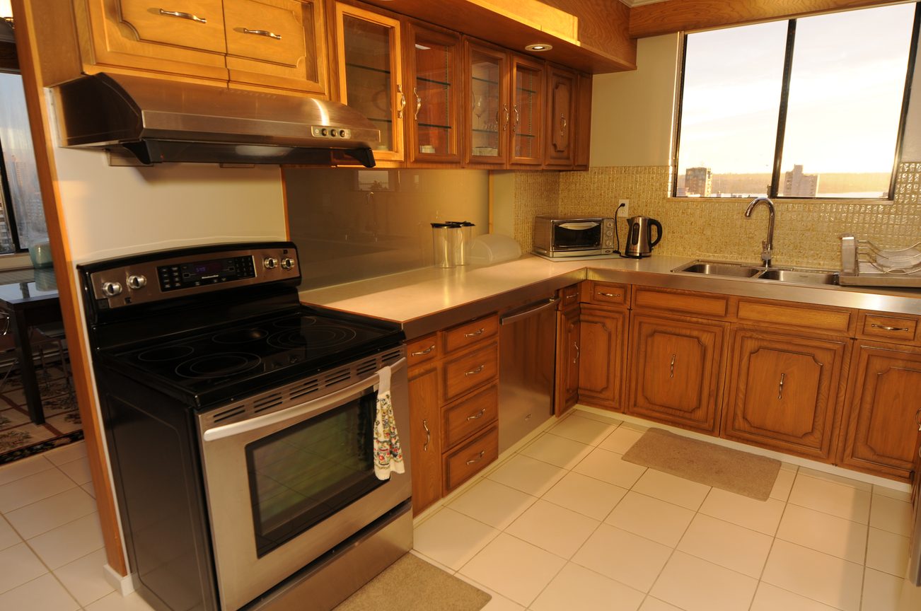 Bright kitchen with stainless steel appliances, city view, and wooden cabinets. - 1501 - 845 Chilco Street, Vancouver Downtown