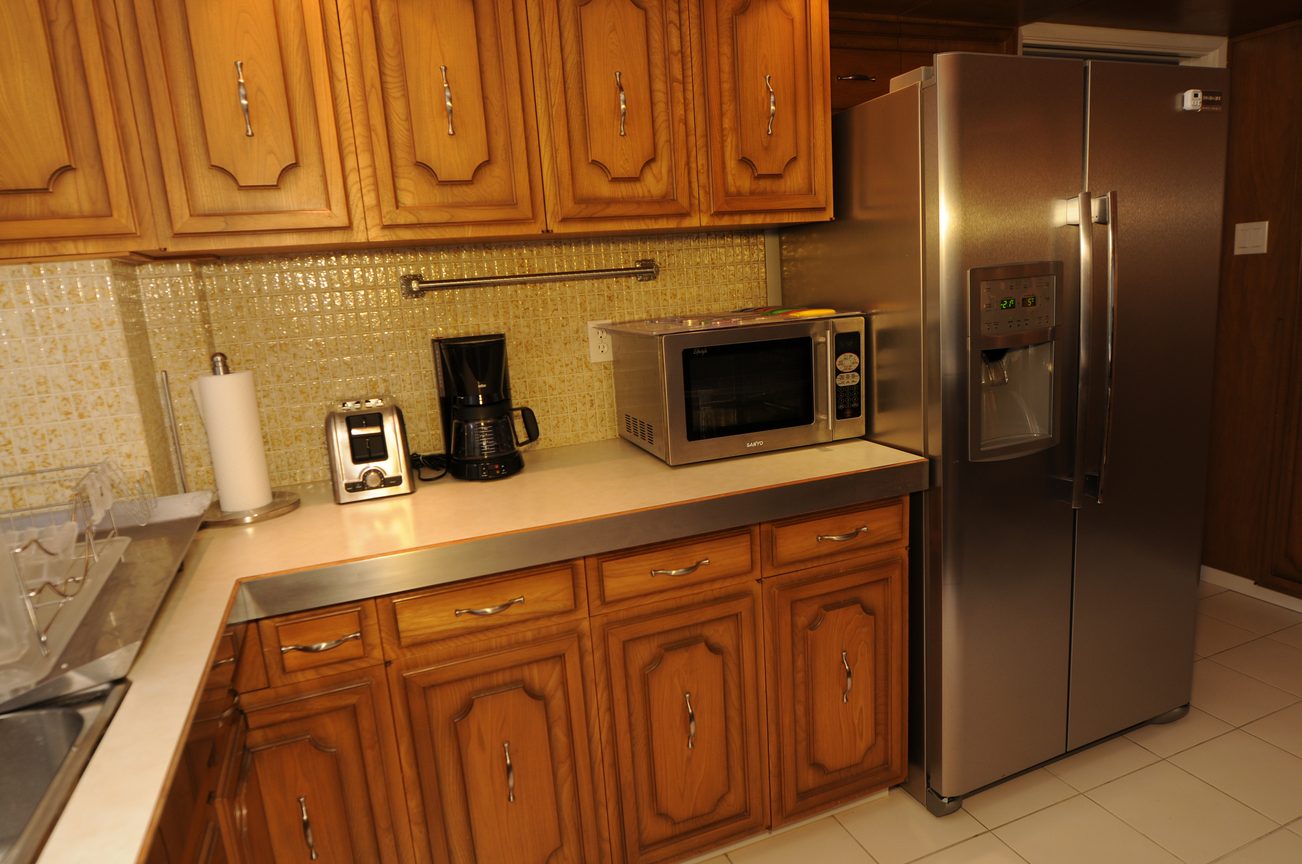 Bright kitchen with wooden cabinets, stainless steel appliances, and a tiled backsplash. - 1501 - 845 Chilco Street, Vancouver Downtown