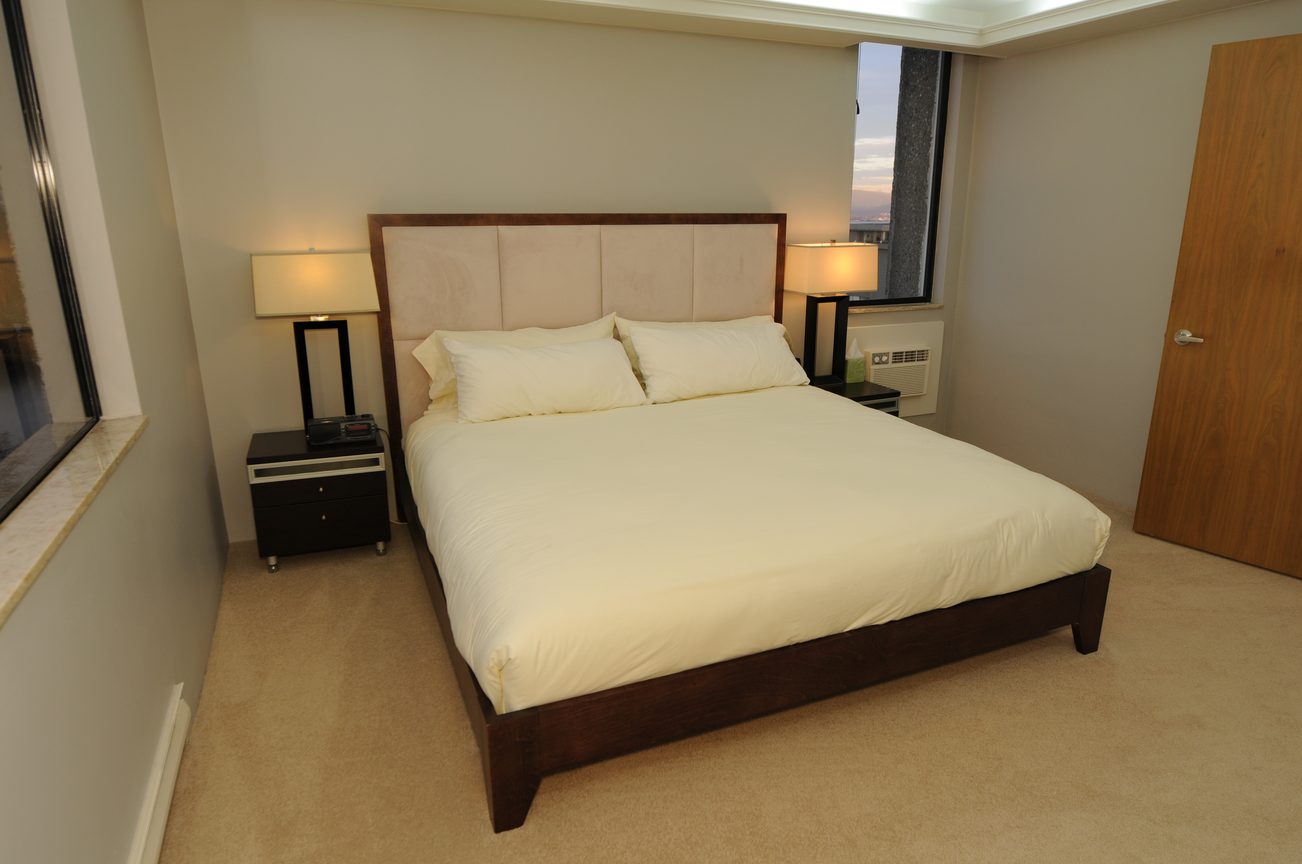 Bright bedroom with modern furniture, city view, and two nightstands with lamps. - 1501 - 845 Chilco Street, Vancouver Downtown