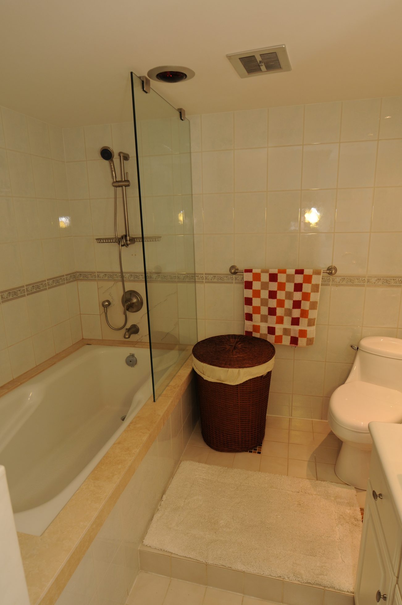 Bathroom with glass shower, tiled walls, and a wicker hamper. - 1501 - 845 Chilco Street, Vancouver Downtown