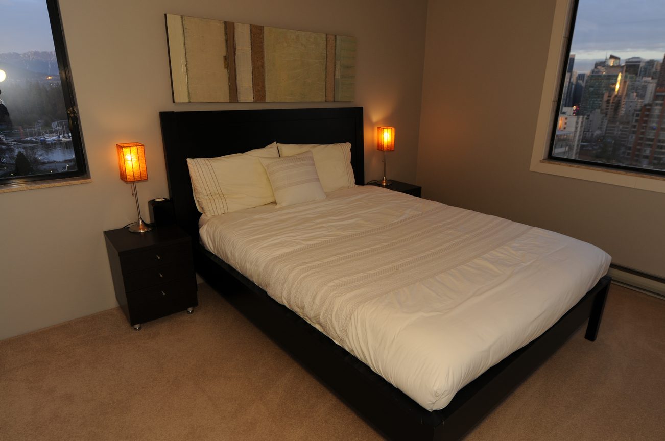 Spacious bedroom with a king-sized bed, city view, and modern decor. - 1501 - 845 Chilco Street, Vancouver Downtown