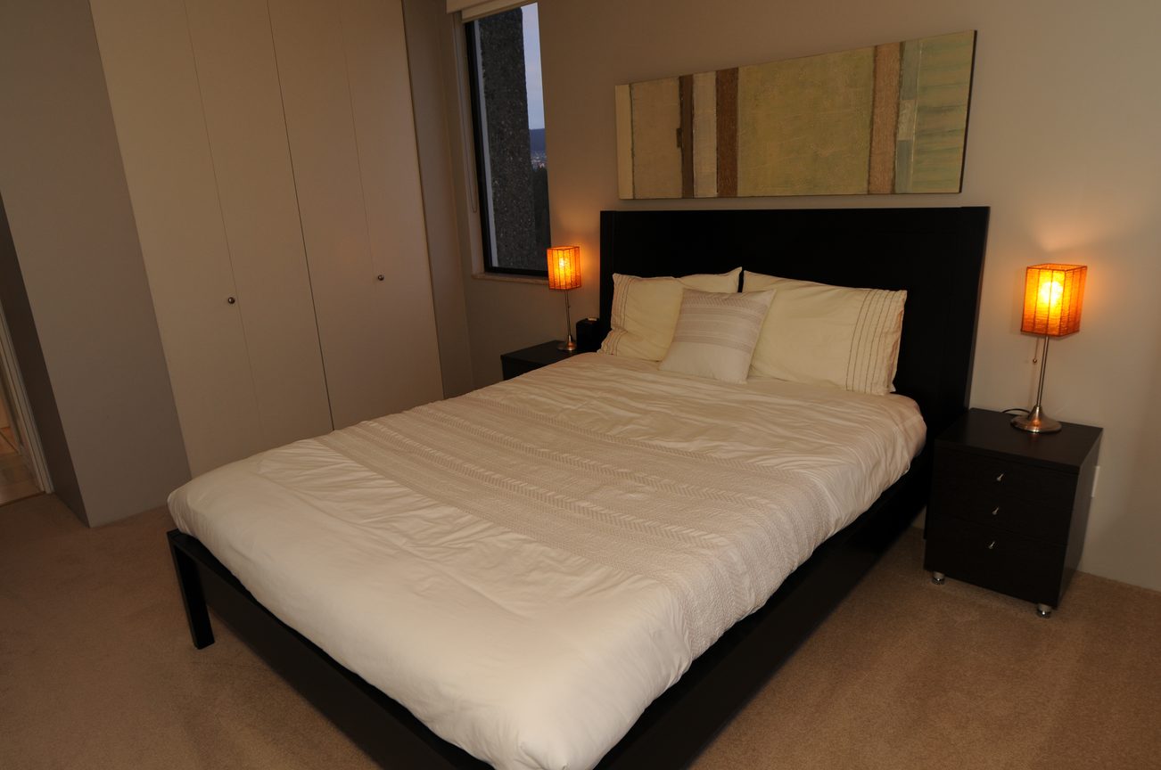 Bright bedroom with modern furniture, two beds, and warm lighting. - 1501 - 845 Chilco Street, Vancouver Downtown