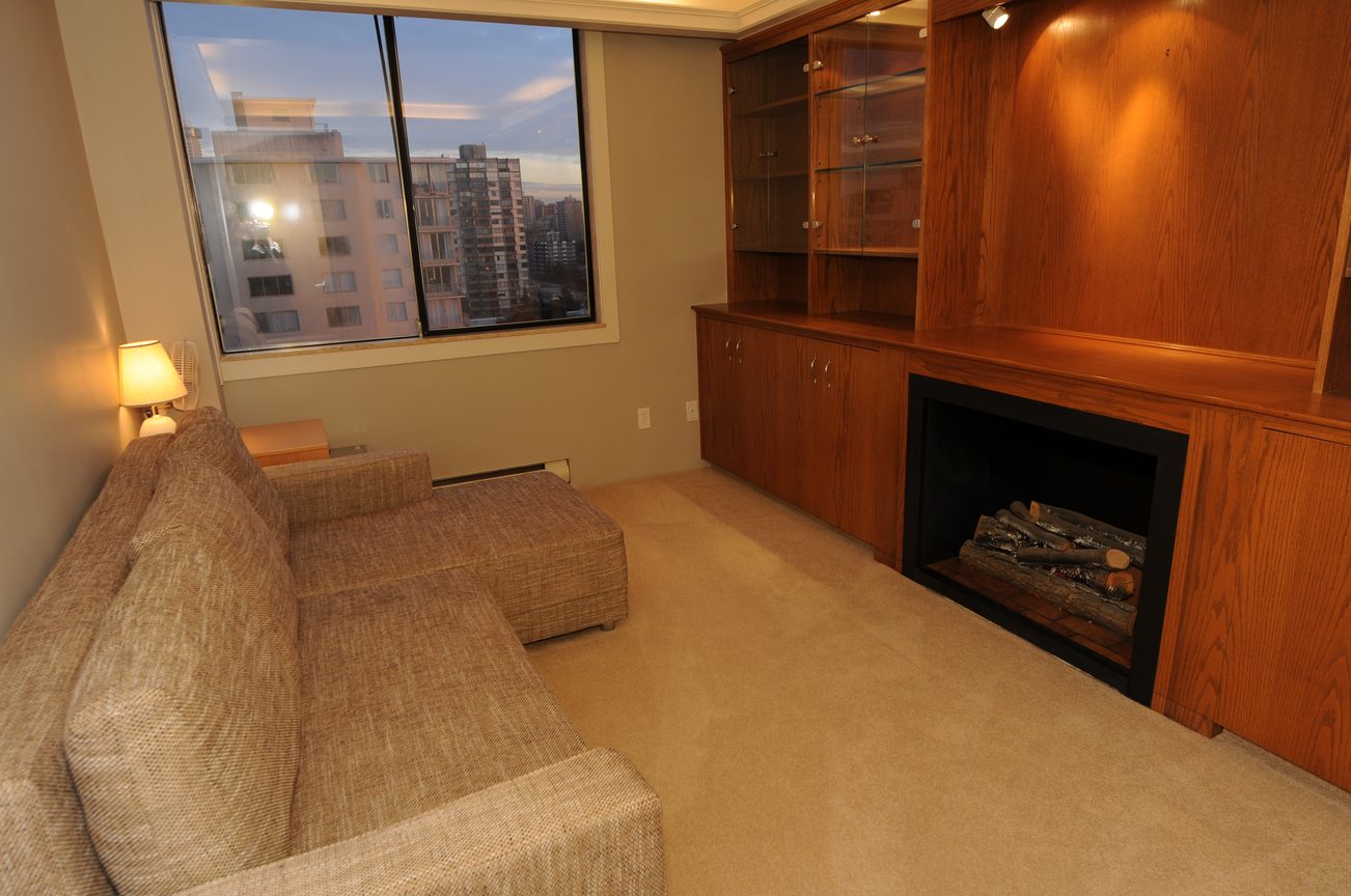 Bright living room with city view, wood-burning fireplace, and modern furnishings. - 1501 - 845 Chilco Street, Vancouver Downtown