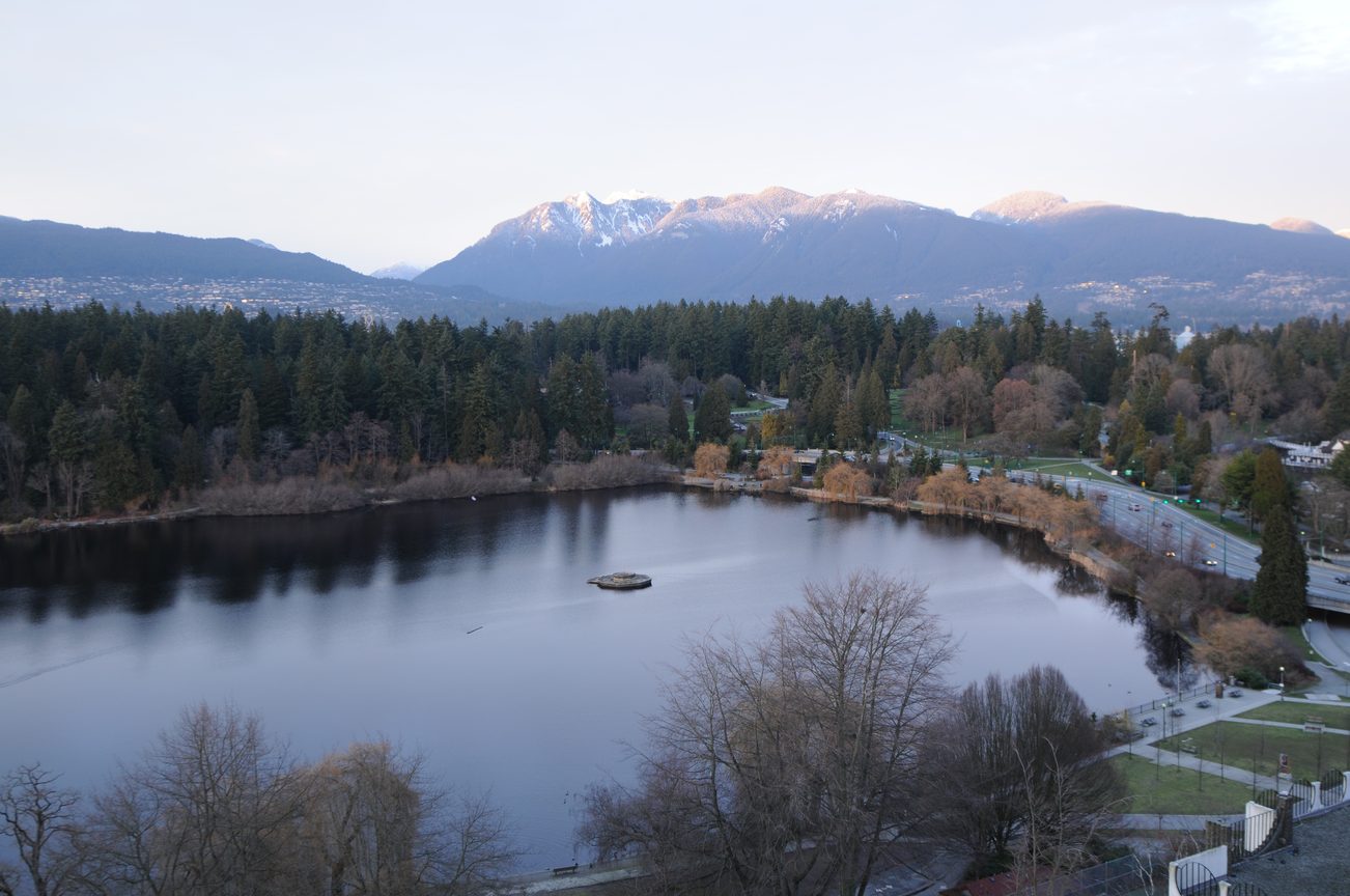 Bright living room with a stunning view of snow-capped mountains and a serene lake. - 1501 - 845 Chilco Street, Vancouver Downtown