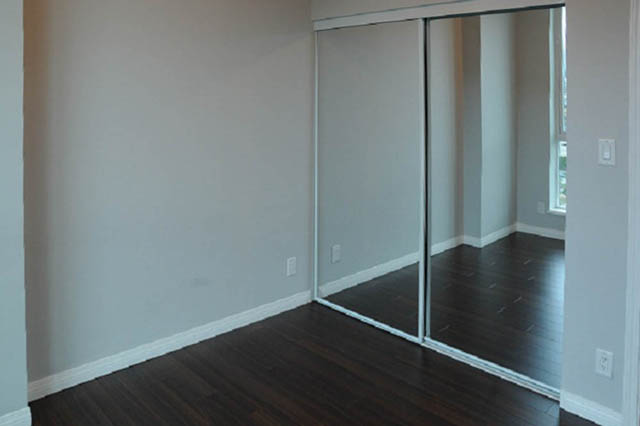 Spacious bedroom with mirrored sliding closet doors and dark hardwood floors. - 1808 - 188 East Esplanade, North Vancouver