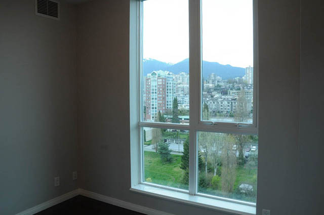 Bright living room with large windows showcasing a city view and greenery. - 1808 - 188 East Esplanade, North Vancouver