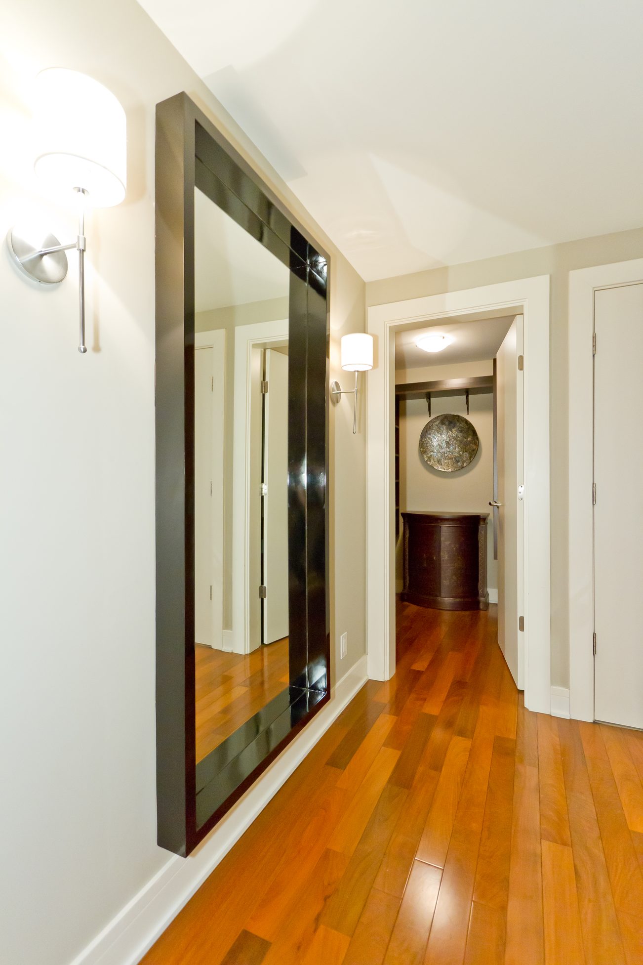 Furnished hallway with hardwood floors and large mirror reflecting adjacent rooms. - 302 - 628 Kinghorne Mews, Vancouver Downtown