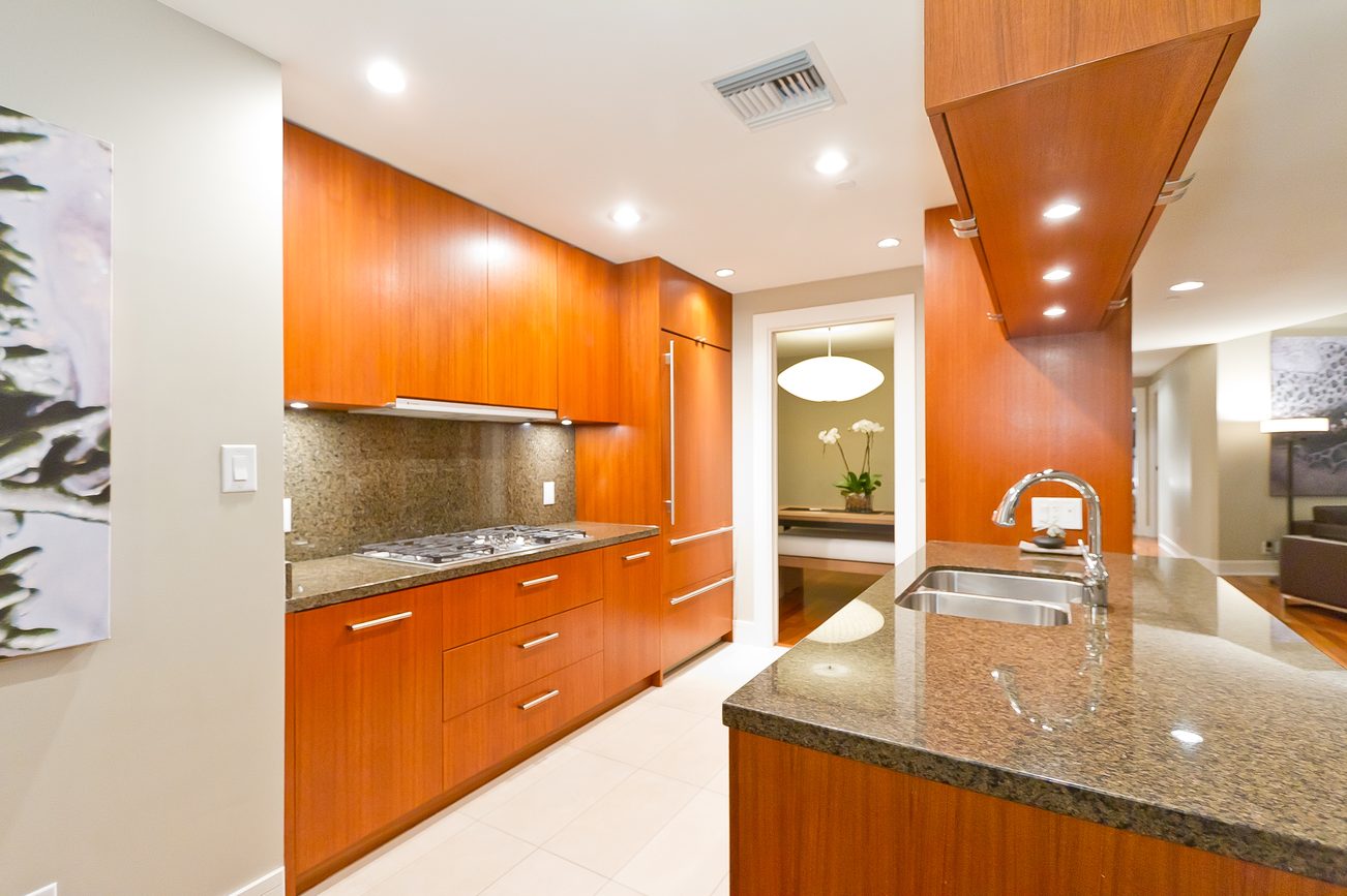 Bright kitchen with modern wood cabinets, granite countertops, and stainless steel appliances. - 302 - 628 Kinghorne Mews, Vancouver Downtown