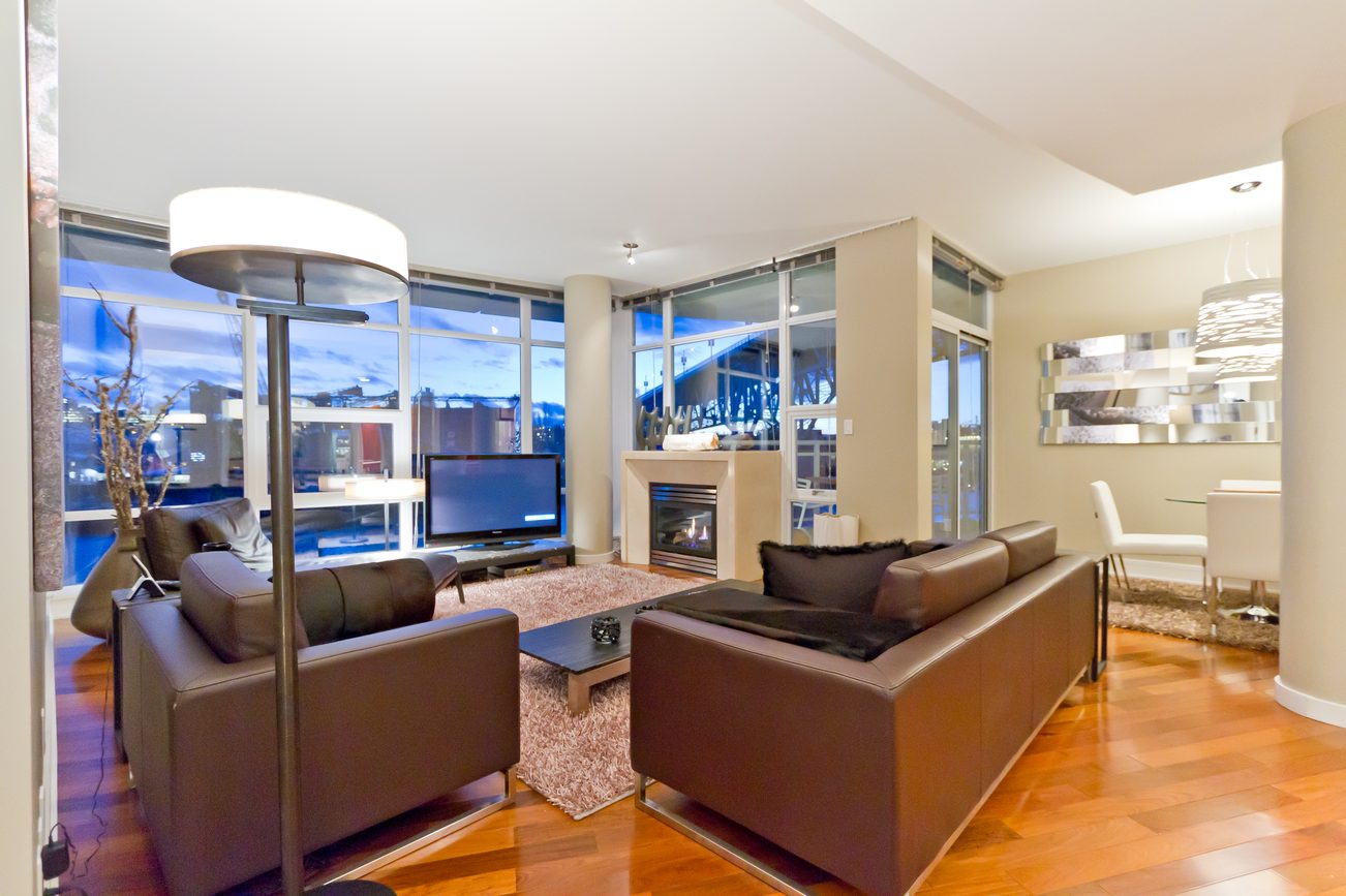 Spacious living room with hardwood floors, city view, and modern furniture. - 302 - 628 Kinghorne Mews, Vancouver Downtown