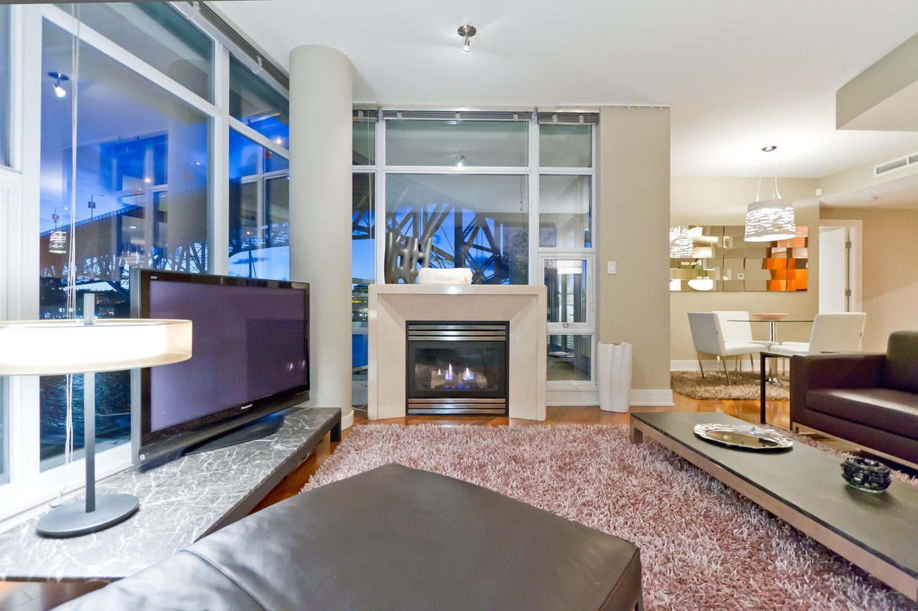 Spacious living room with fireplace, city view, and modern decor. - 302 - 628 Kinghorne Mews, Vancouver Downtown