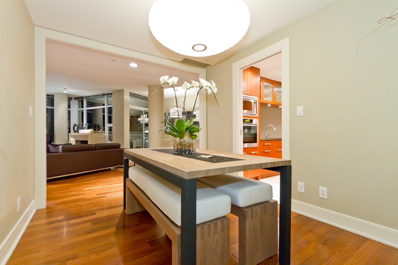 Modern dining area with sleek table, plush bench seating, and hardwood floors. - 302 - 628 Kinghorne Mews, Vancouver Downtown