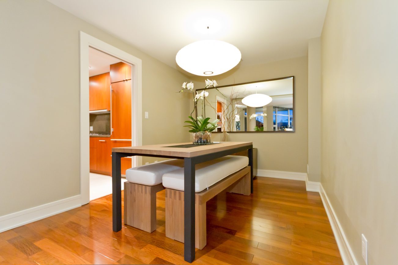 Furnished dining area with hardwood floors, modern table, and kitchen in background. - 302 - 628 Kinghorne Mews, Vancouver Downtown