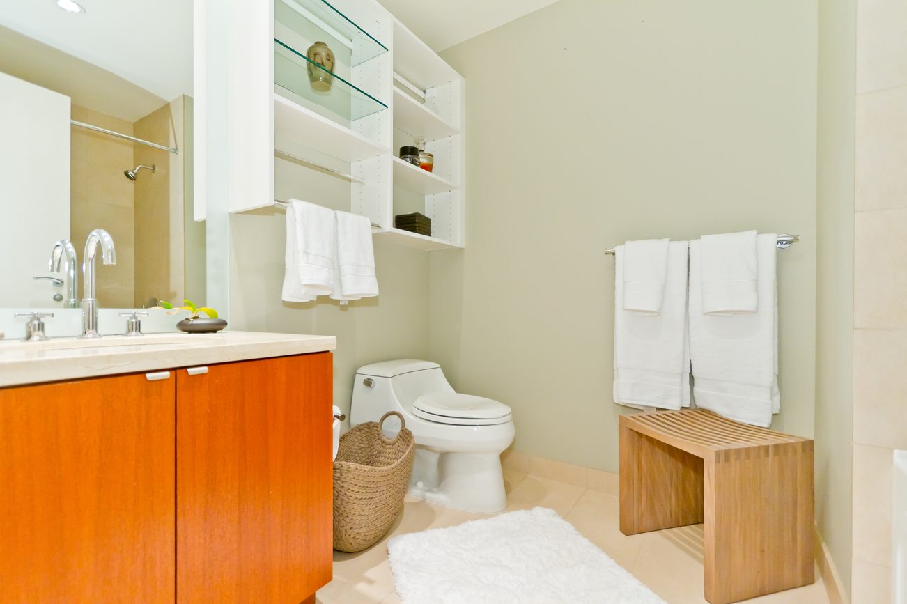 Bright bathroom with wooden vanity, white towels, and a cozy bath mat. - 302 - 628 Kinghorne Mews, Vancouver Downtown