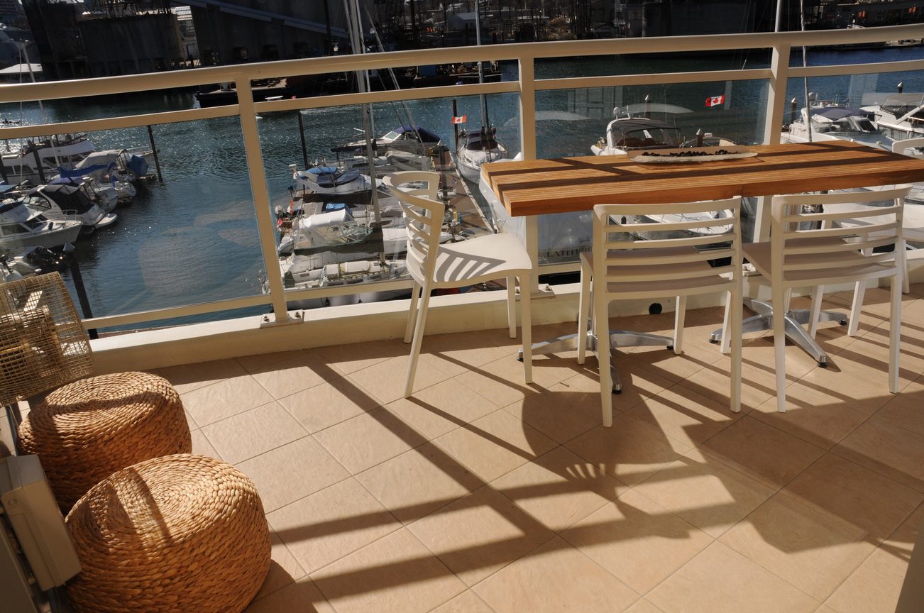 Furnished balcony with a wooden table, white chairs, and a view of boats and water. - 302 - 628 Kinghorne Mews, Vancouver Downtown