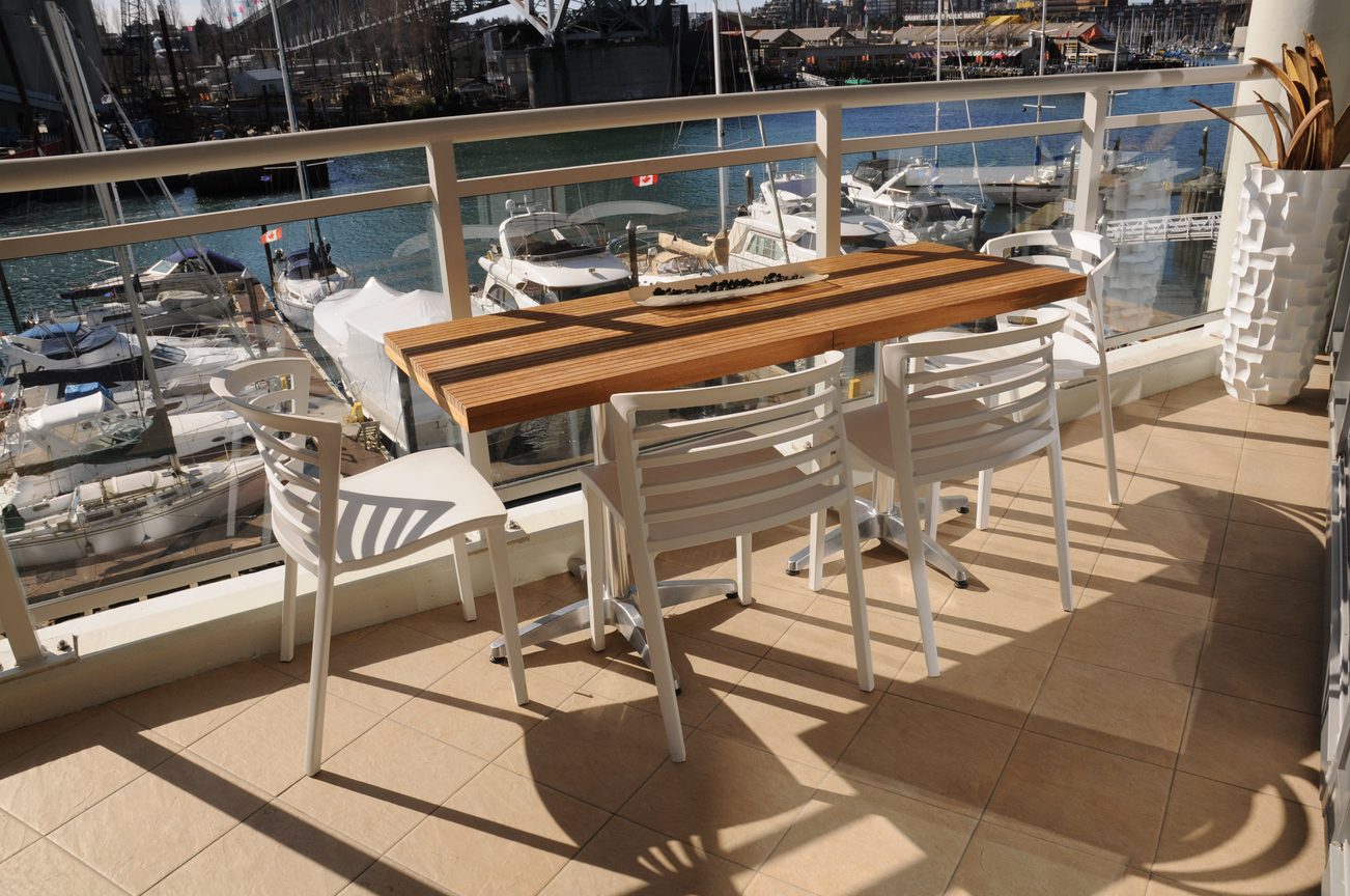 Furnished dining area with a view of the marina and boats, featuring a wooden table and white chairs. - 302 - 628 Kinghorne Mews, Vancouver Downtown
