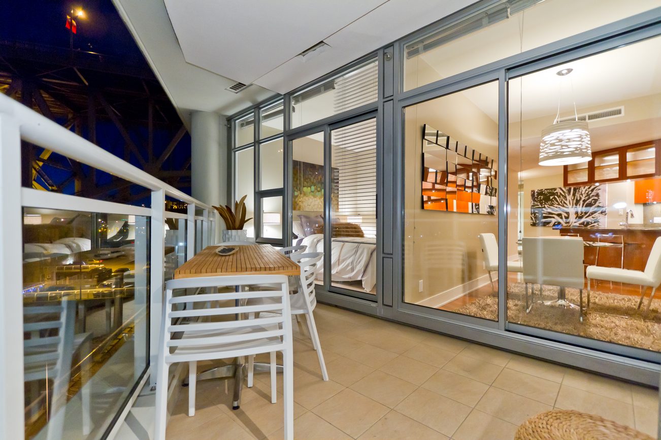 Bright living room with glass sliding doors, modern decor, and city view. - 302 - 628 Kinghorne Mews, Vancouver Downtown