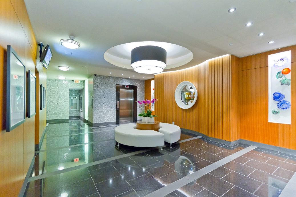 Furnished living room with modern decor, wood paneling, and sleek lighting. - 302 - 628 Kinghorne Mews, Vancouver Downtown