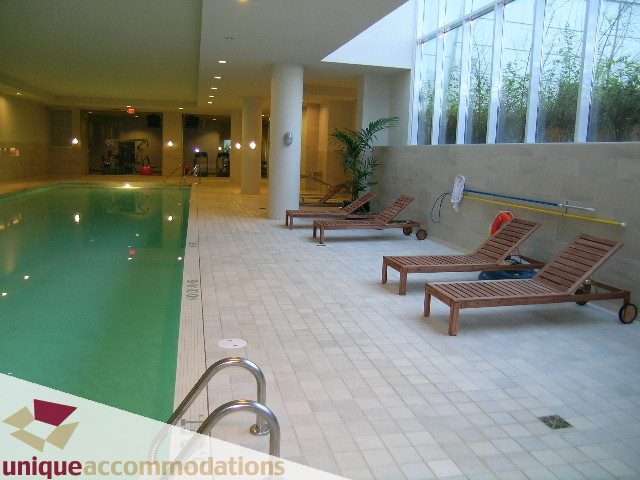 Spacious indoor pool area with lounge chairs and large windows. - 302 - 628 Kinghorne Mews, Vancouver Downtown