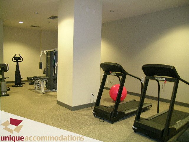 Fitness room with treadmills and exercise equipment, carpeted floor. - 302 - 628 Kinghorne Mews, Vancouver Downtown