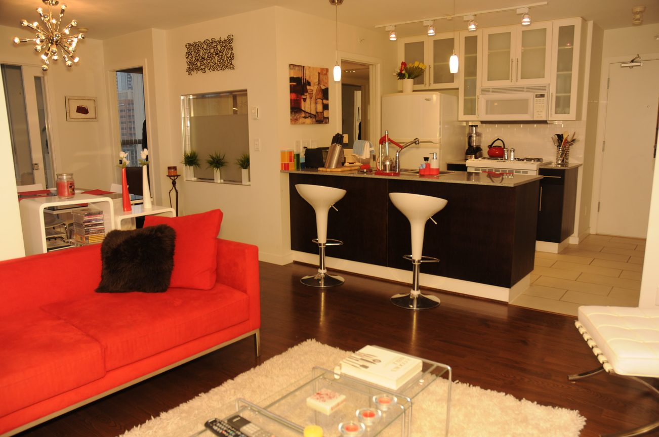 Bright living room with red sofa, hardwood floors, and a city view. - 1808 - 1225 Richards Street, Vancouver Downtown