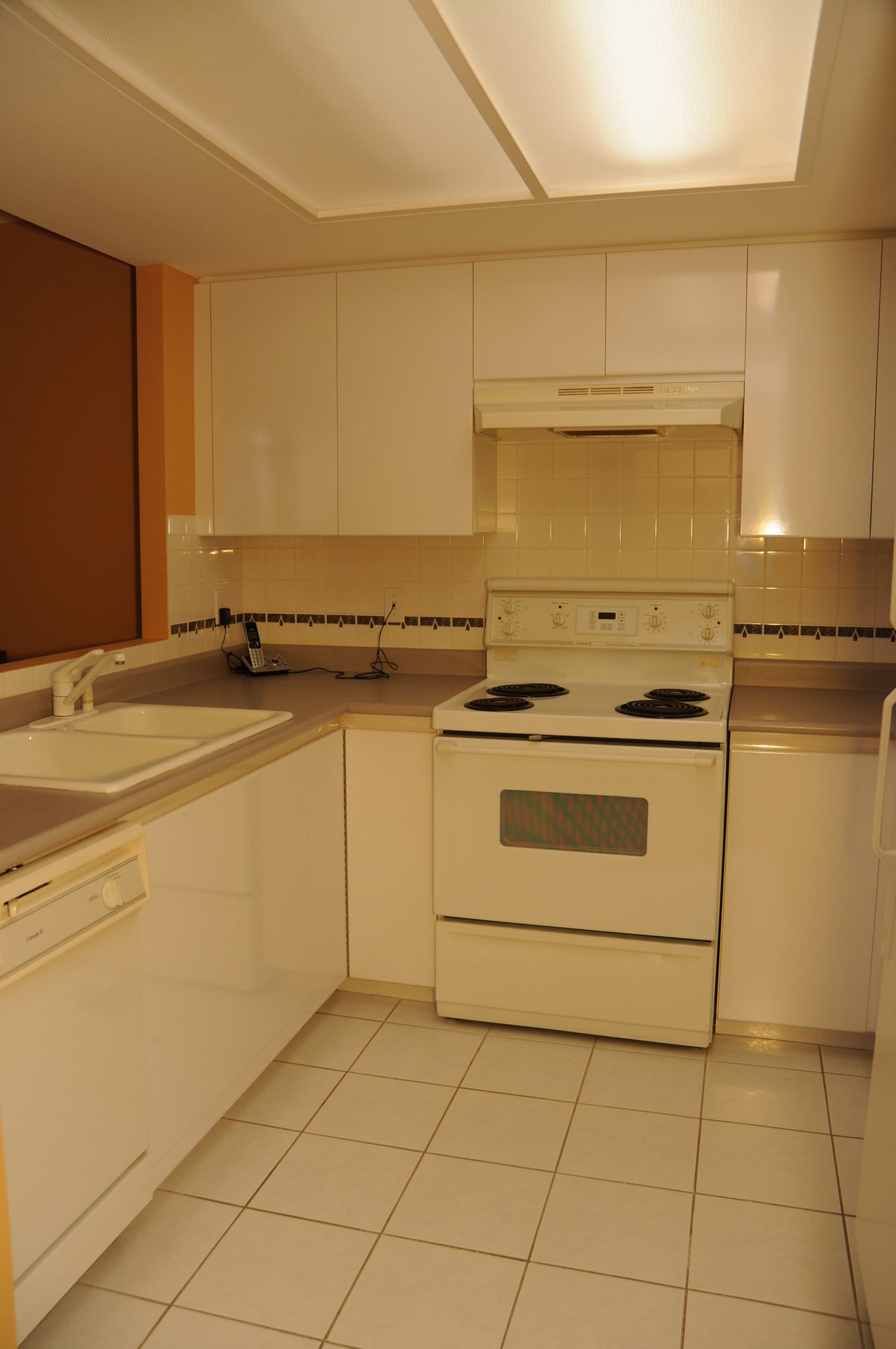 Bright kitchen with white cabinets, beige countertops, and a white stove, clean and ready for use. - 1705-867 Hamilton Street, Vancouver Downtown