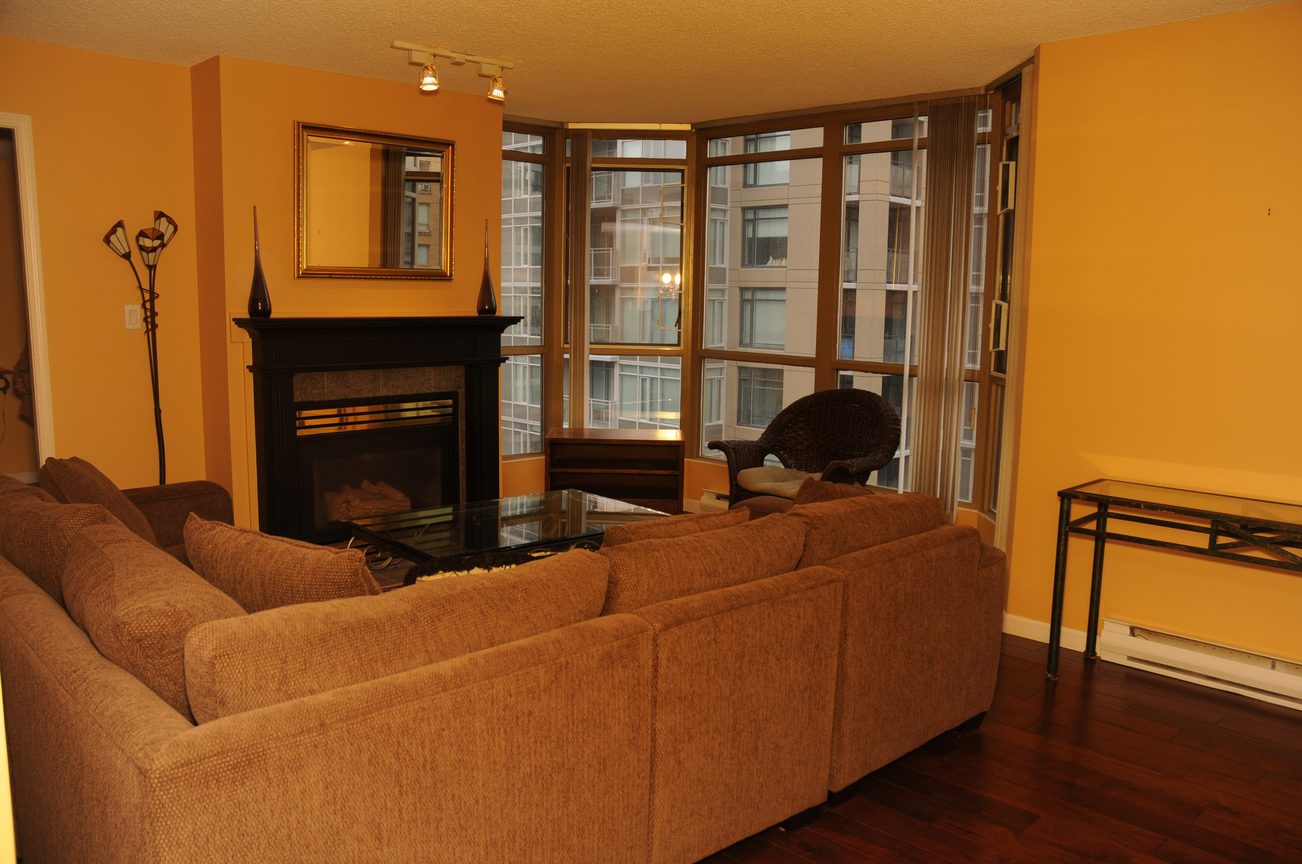 Furnished living room with hardwood floors, city view, and a cozy fireplace. - 1705-867 Hamilton Street, Vancouver Downtown