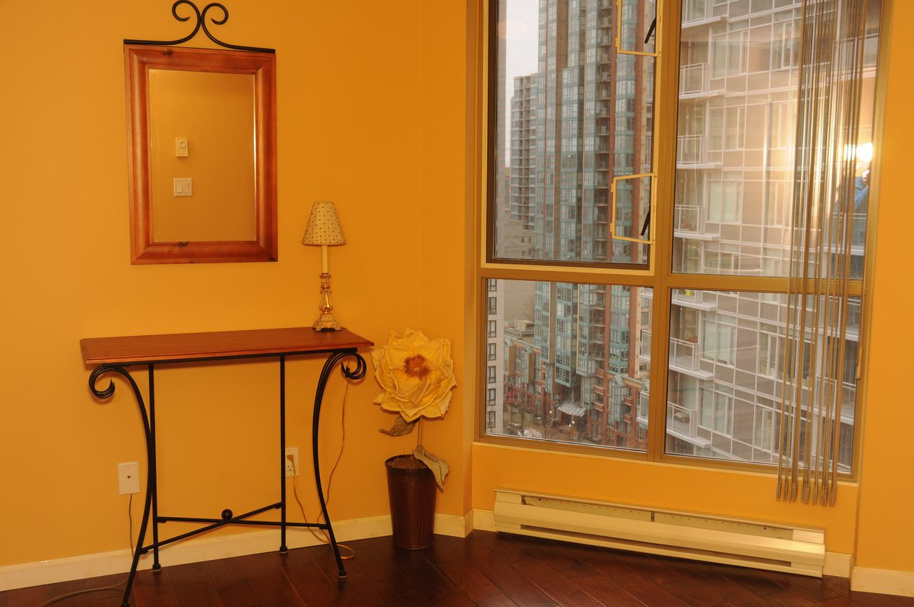Bright living room with hardwood floors, city view, and a wooden console table. - 1705-867 Hamilton Street, Vancouver Downtown