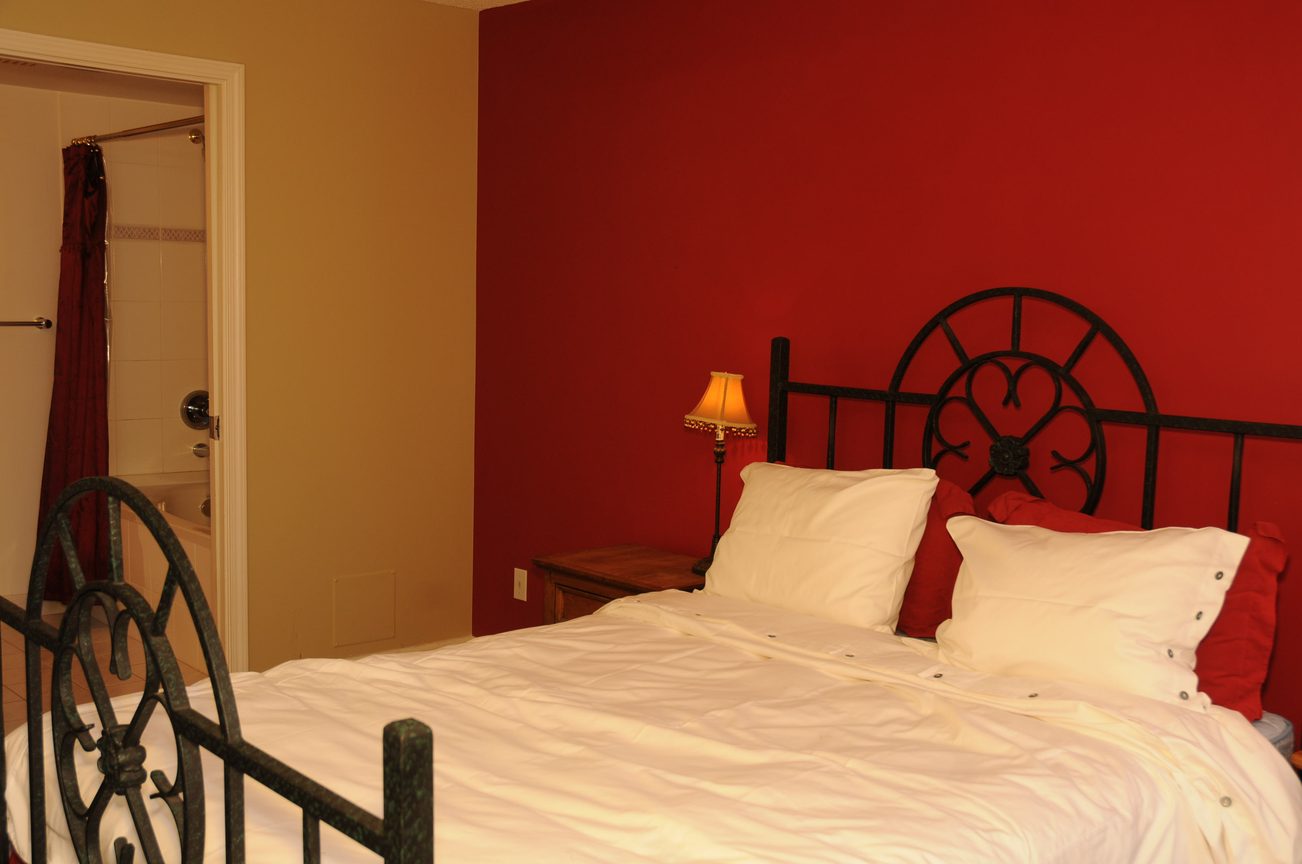 Furnished bedroom with red walls and black metal headboard, cozy ambiance. - 1705-867 Hamilton Street, Vancouver Downtown