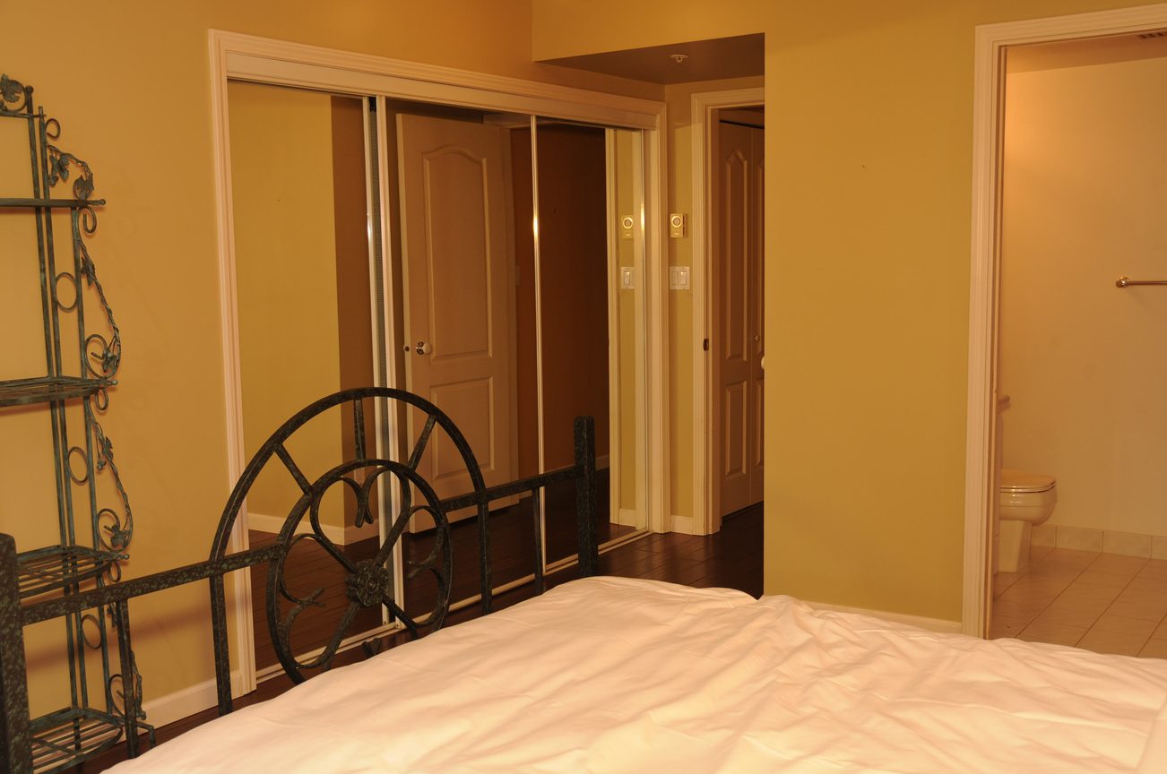 Furnished bedroom with wrought iron bed frame and sliding closet doors. - 1705-867 Hamilton Street, Vancouver Downtown