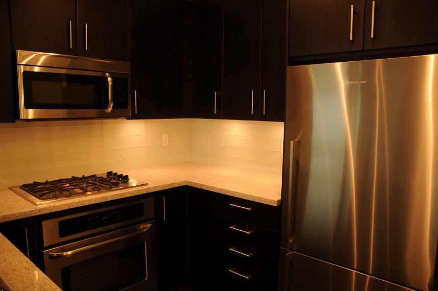 Bright kitchen with granite countertops, stainless steel appliances, and dark wood cabinets. - G07 - 119 West 22nd Avenue, North Vancouver