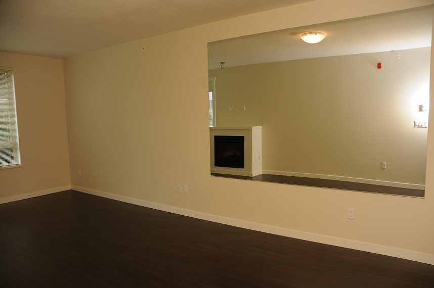 Bright living room with hardwood floors and a fireplace, ready for furnishings. - G07 - 119 West 22nd Avenue, North Vancouver