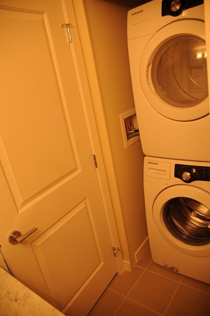 Laundry room with stacked washer and dryer, light wood flooring. - G07 - 119 West 22nd Avenue, North Vancouver